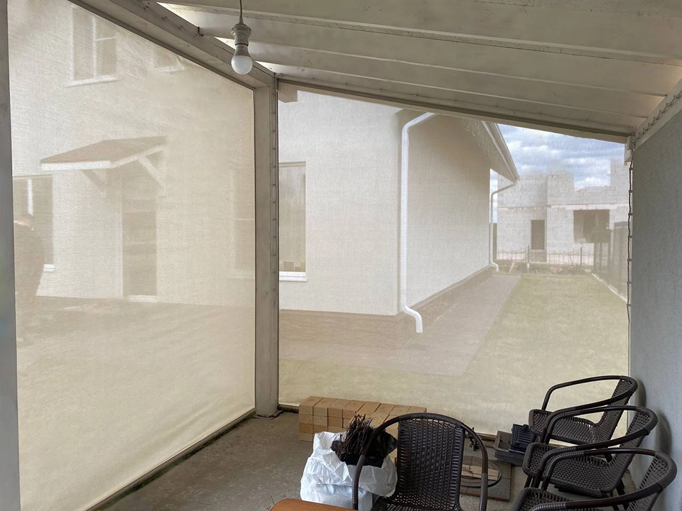 Вид изнутри беседки через светло-серые защитные шторы