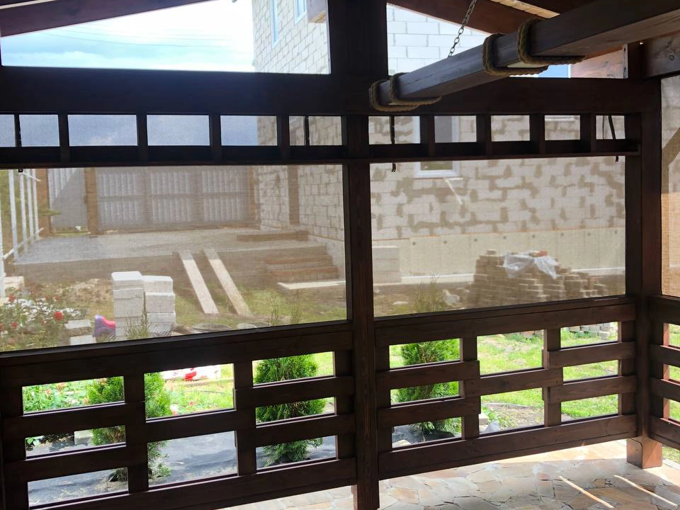 Вид изнутри беседки через бежевые защитные шторы